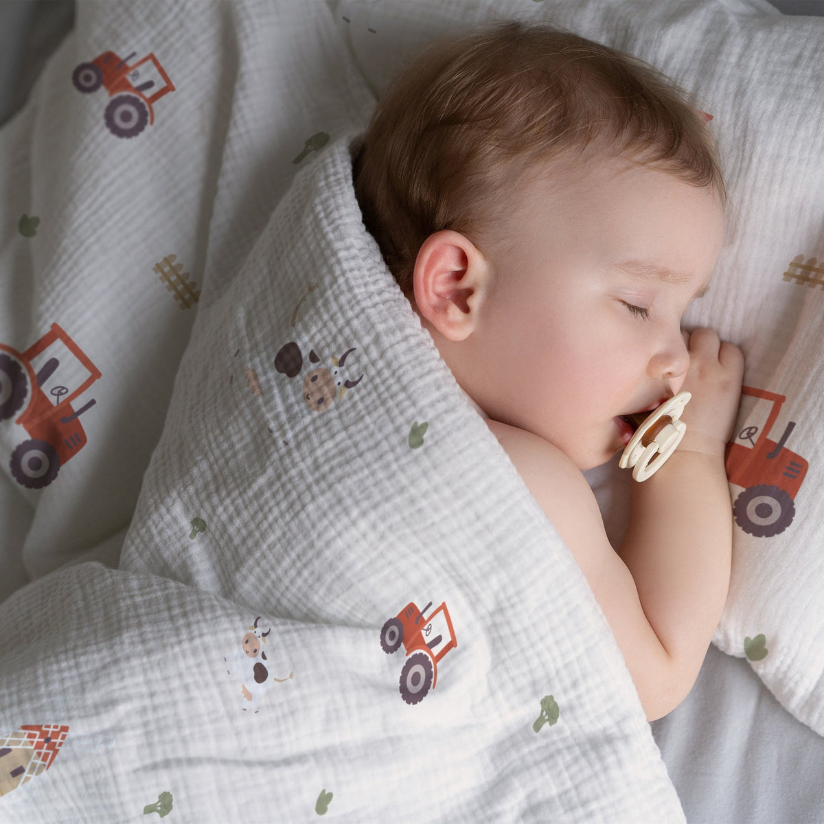 Un enfant endormi, blotti dans du linge de lit Leslis aux motifs Sweet Farm.