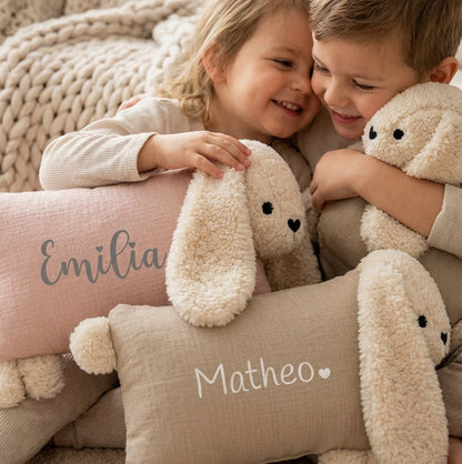 Zwei Kinder halten personalisierte Kuschelhasen mit den Namen „Emilia“ und „Matheo“ im Arm.