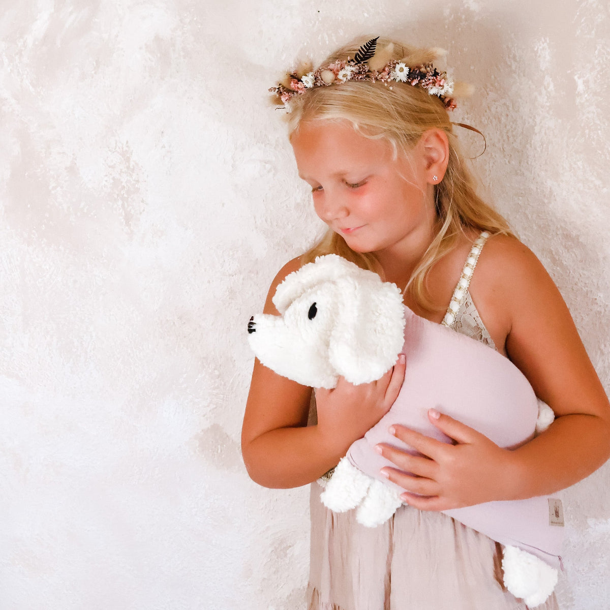 Kind hält einen rosa Kuschelhund im Arm.
