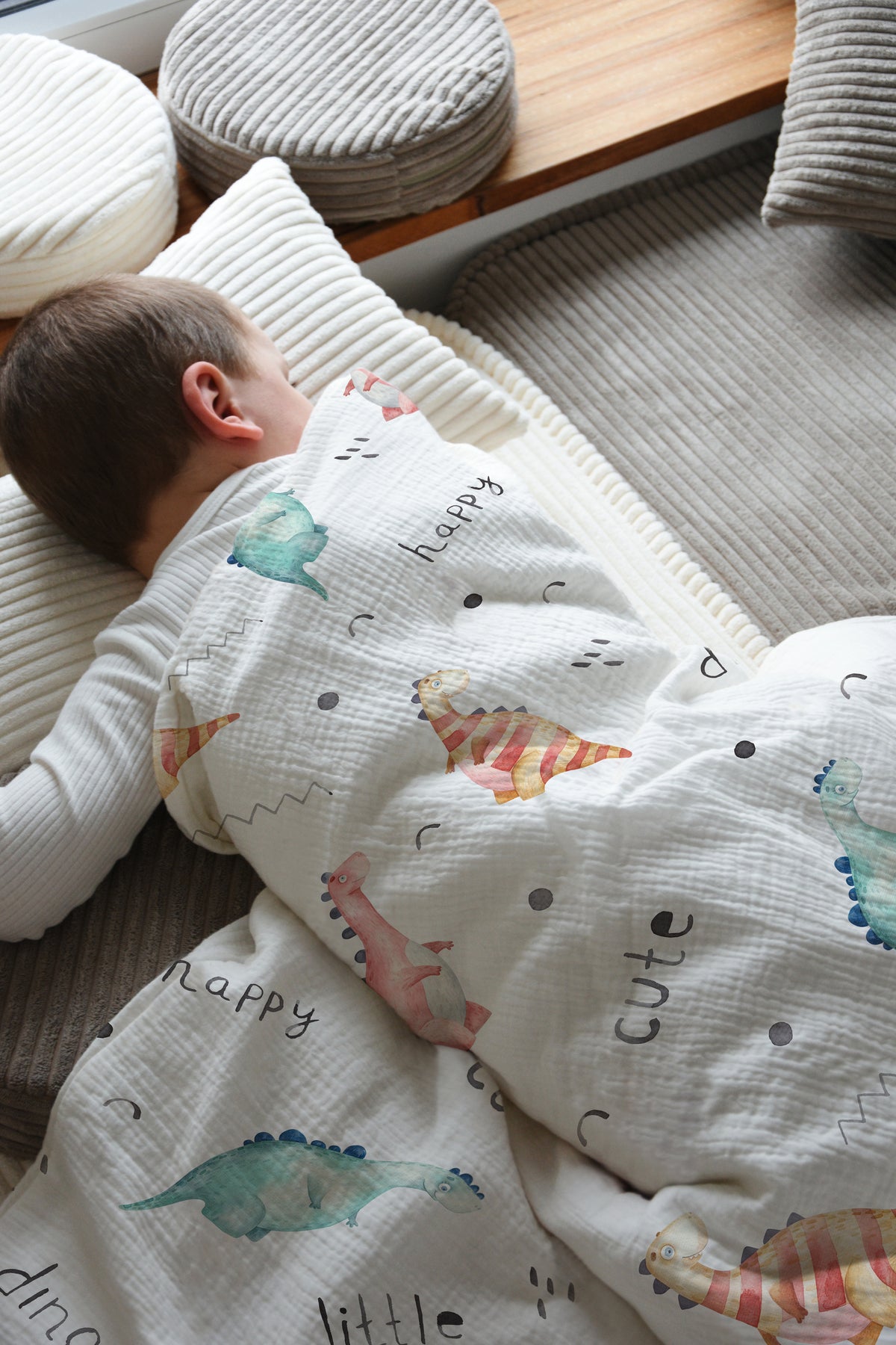 Kleinkind schläft unter Leslis-Kinderbettwäsche „Little Dino“ neben einem Fenster.