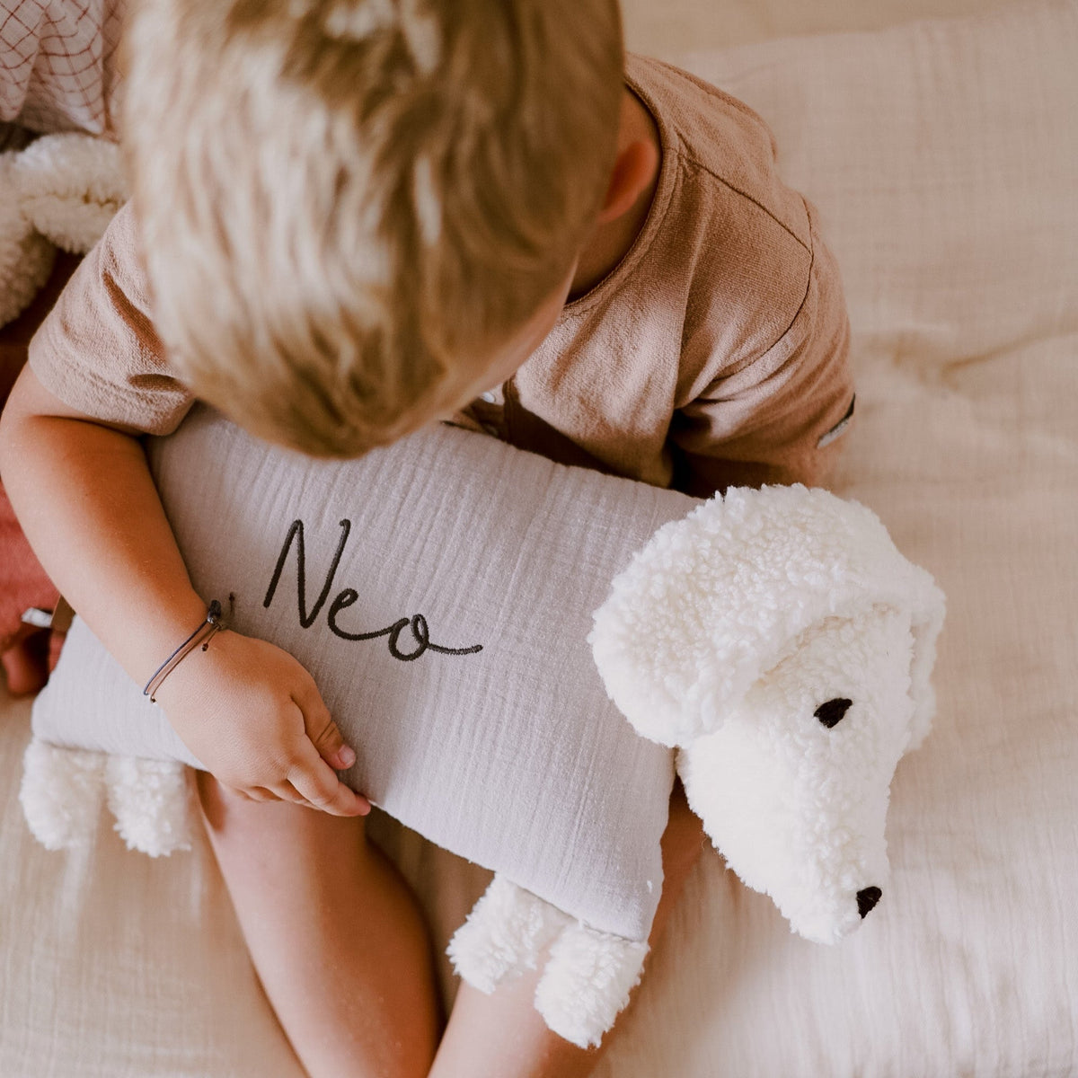 Kind hält einen Kuschelhund mit aufgesticktem Namen „Neo“ auf dem Stoffkörper.
