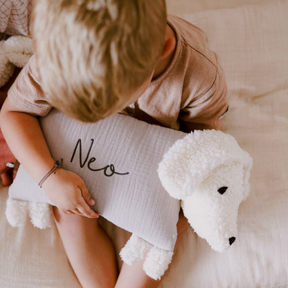 Kind hält einen Kuschelhund mit aufgesticktem Namen „Neo“ auf dem Stoffkörper.