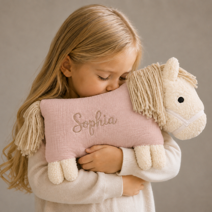 Kind kuschelt mit einem rosa Kuschelpferd mit aufgesticktem Namen „Sophia“.