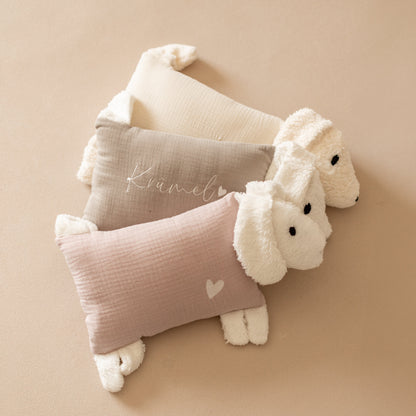 Drei Kuschelhunde mit naturfarbenem, beigem und rosa Stoffkörper liegen nebeneinander.
