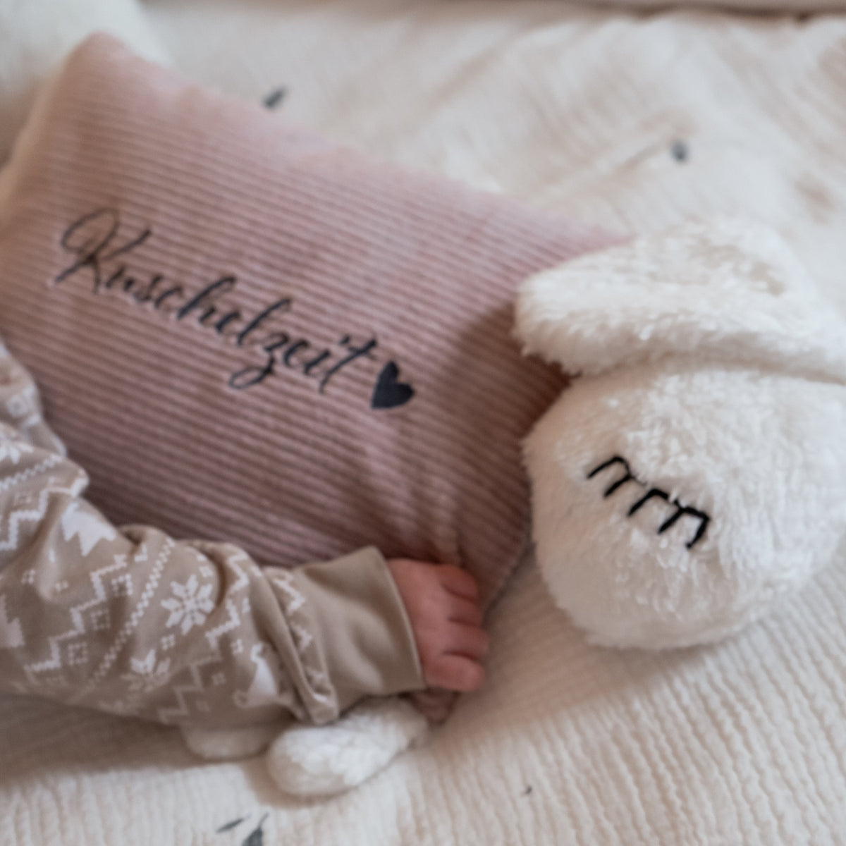 Nahansicht zweier personalisierter Kuschelschafe mit aufgestickten Namen auf Kopf und Stoffkörper.