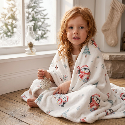Kind mit der Kuscheldecke „Pinguine“ am Fenster.